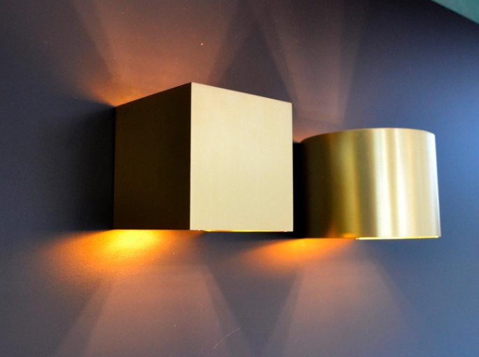 Deux cubes muraux sombre et doré diffusant la lumière vers le plafond et le sol
