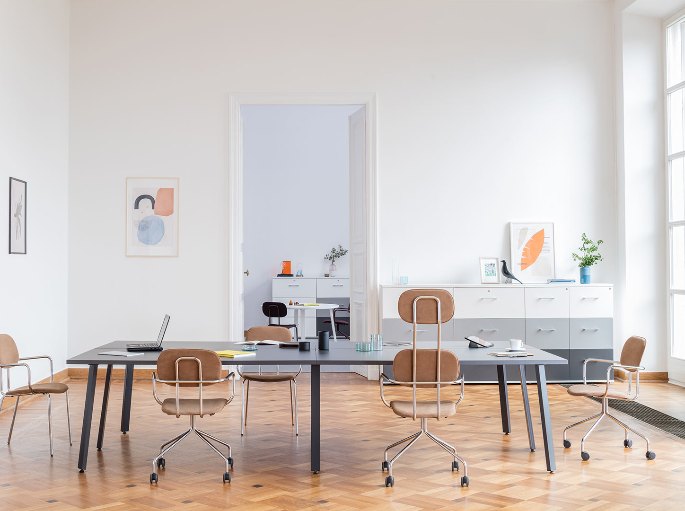 Table collective et sièges à roulettes dans une salle claire
