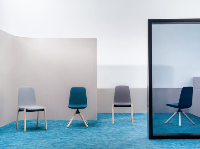 Trois sièges en tissu bleu et gris posés sur une moquette turquoise près d'un miroir