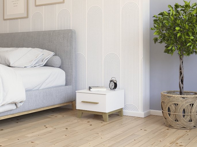 Petit meuble de nuit sur pieds fins portant un réveil, dans une chambre au parquet clair