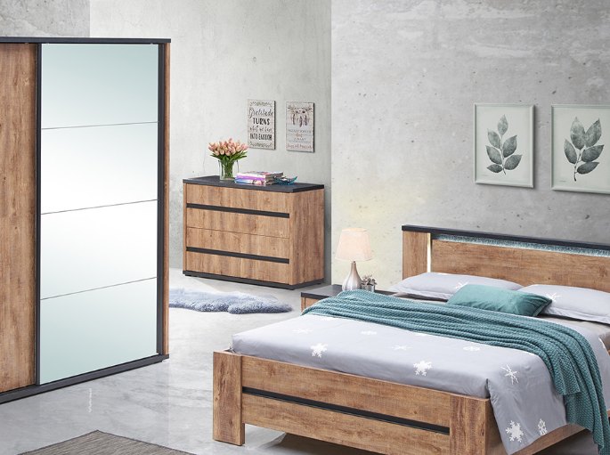 Meuble de chambre en bois foncé avec lampe, bouquet et cadres au-dessus du plateau