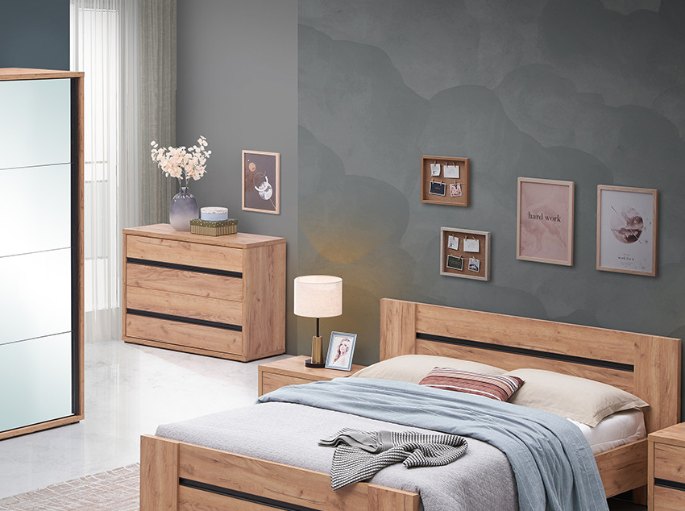 Rangement à tiroirs en bois naturel avec vase fleuri et cadres dans une chambre au mur gris