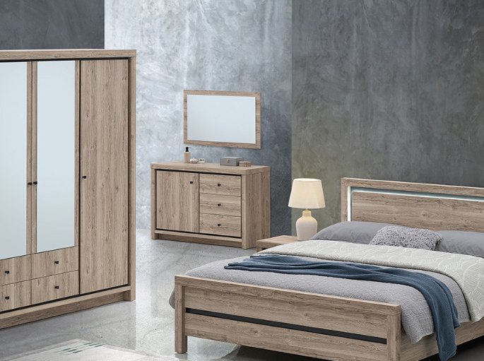 Meuble bas à tiroirs en bois clair avec lampe de chevet et miroir posé dans une chambre