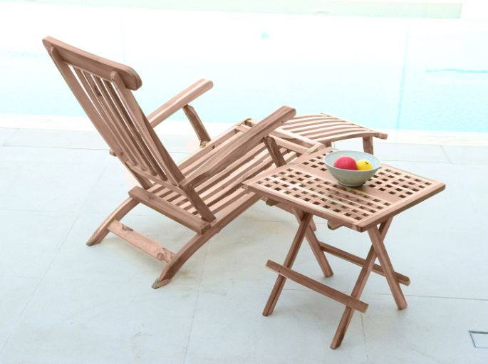 Assise allongée en bois clair, dossier redressé et repose-jambes déplié au bord d’un bassin