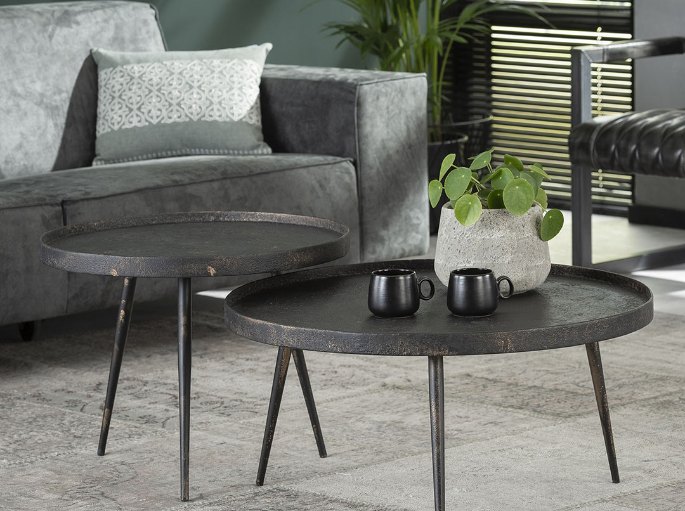 Guéridons ronds à plateau sombre installés à côté d'un fauteuil gris