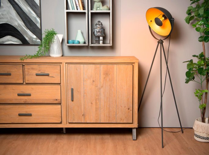 Pied à projecteur orienté vers le mur, à côté d'un buffet en bois clair