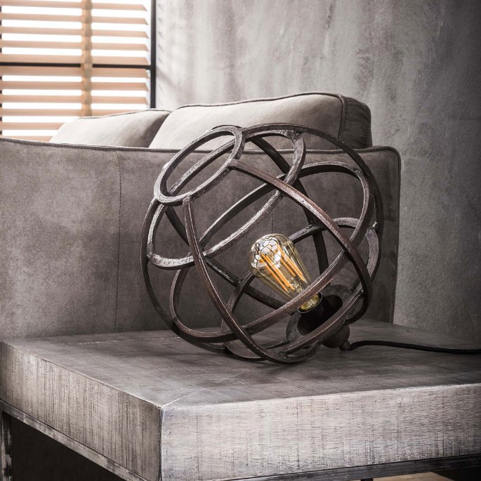 Globe lumineux cuivré posé près d'un canapé en tissu gris