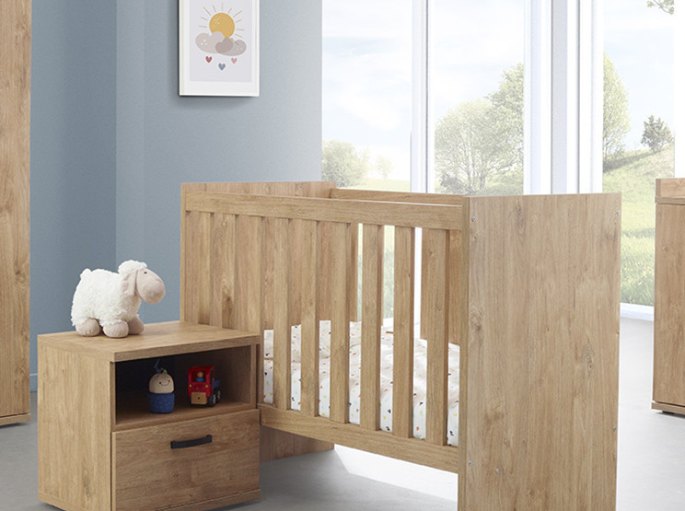 Couchage à barreaux en bois clair dans une chambre de bébé lumineuse