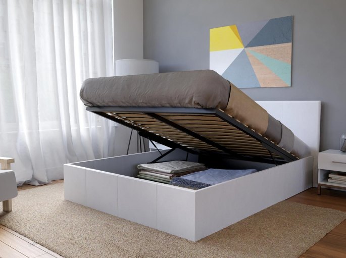 Espace de stockage ouvert sous un couchage deux places habillé de tissu clair