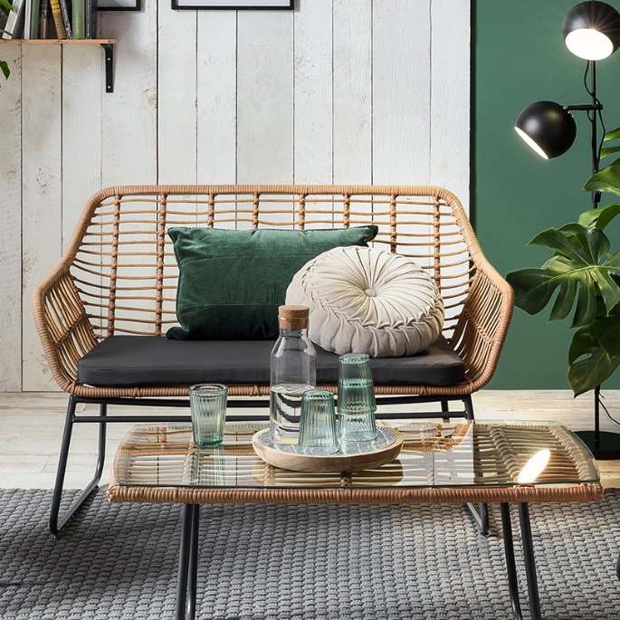 Banquette et fauteuils en fibre synthétique claire autour d’une table basse vitrée