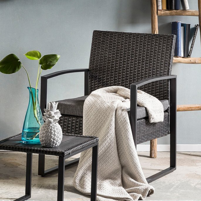 Siège tressé foncé et guéridon assorti installés sous un abri de terrasse