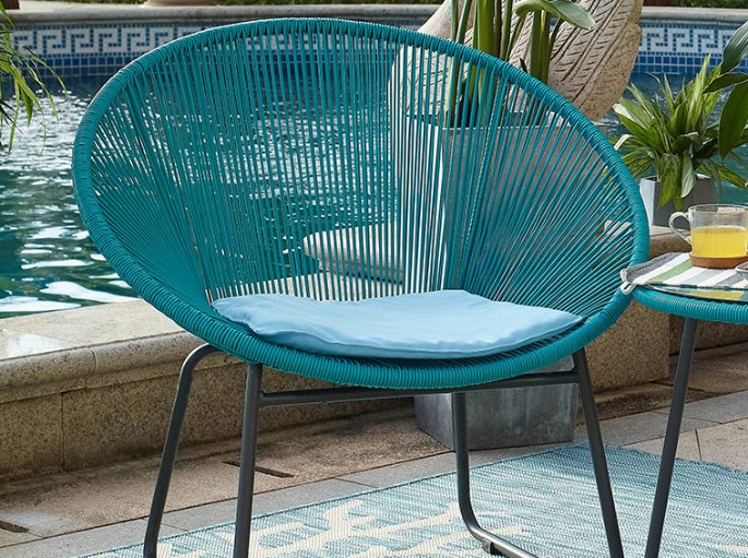 Fauteuil d’extérieur en plastique coloré exposé en plein soleil au bord d’un bassin