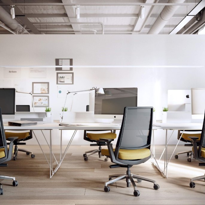 Plateau de bureau blanc et assise à dossier résille dans un espace tertiaire