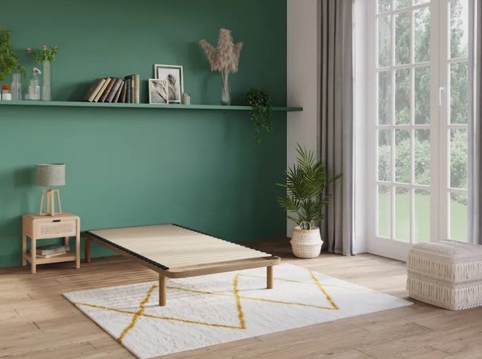 Chambre verte avec base de couchage basse en pin clair, plan fermé posé sur tapis graphique