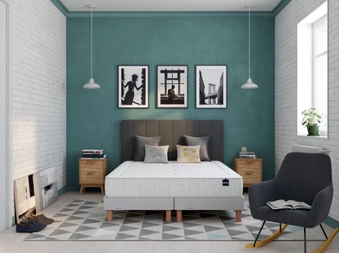 Base de couchage habillée de coutil gris posée sur pieds bois dans une chambre aux murs bleu-vert