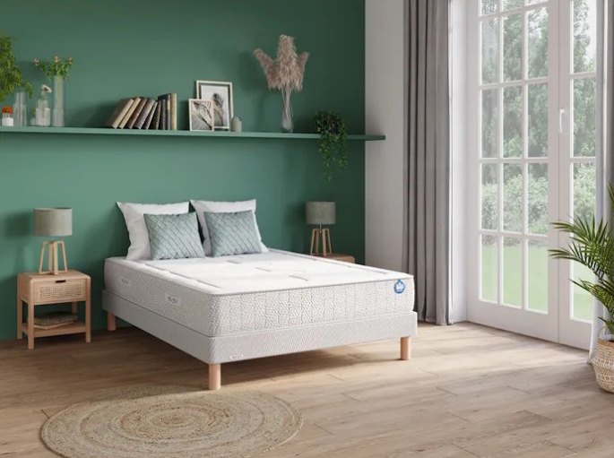 Couchage double garni de deux oreillers plats, dans une chambre aux murs verts