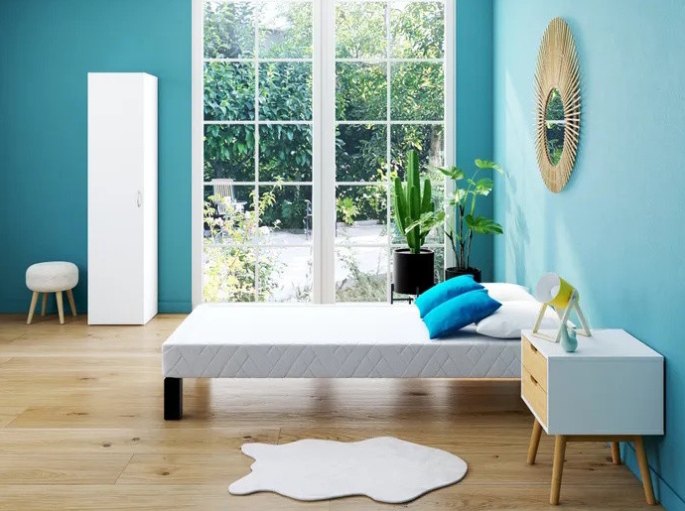 Chambre lumineuse où la base du couchage est habillée d'un coutil clair