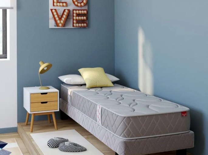 Couchage tapissé d'une place aligné sur un mur bleu avec table de chevet en bois clair
