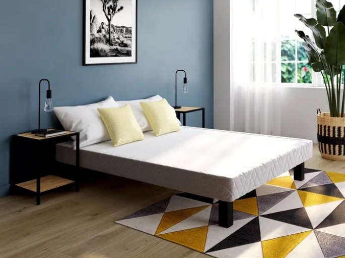 Ensemble literie de deux places vu de face avec coussins jaunes et tapis à motifs géométriques