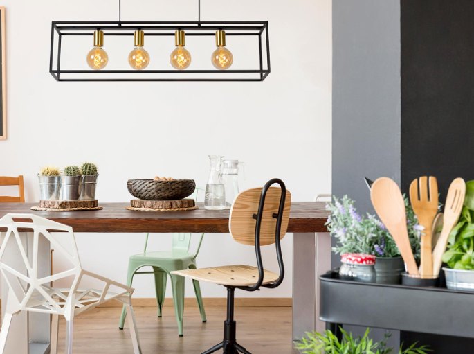 Barre à quatre ampoules filament au-dessus d'une table de repas en bois et de chaises dépareillées
