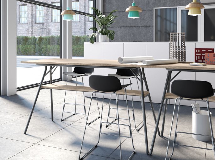 Plateau haut rectangulaire en bois et tabourets noirs dans un espace de coworking