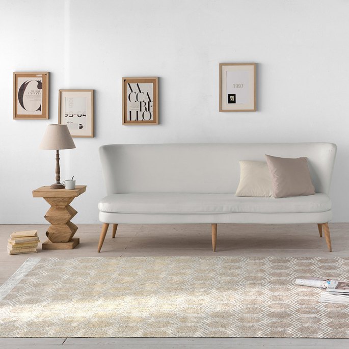 Banquette claire dans une pièce lumineuse au-dessus d'une grande surface tissée bicolore