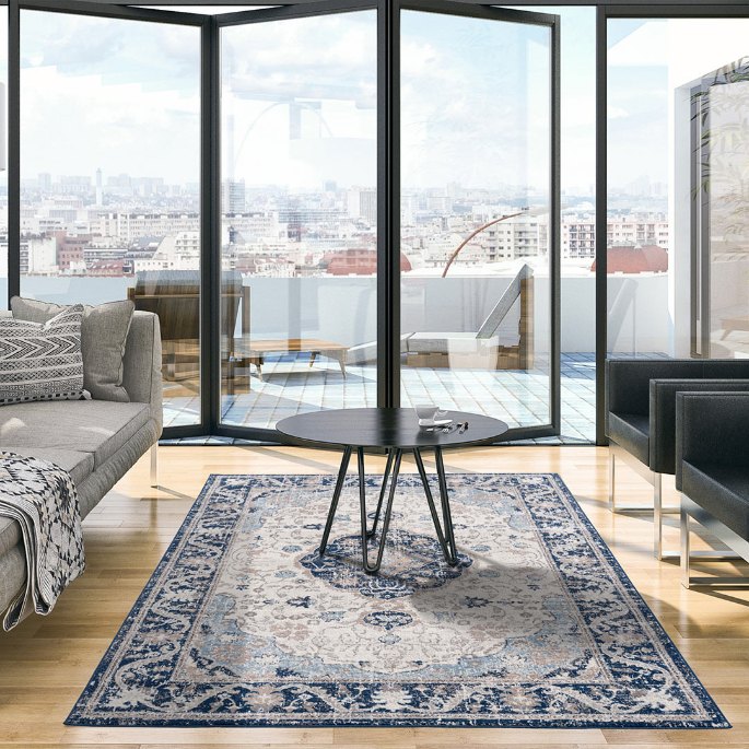 Table ronde en verre au centre d’un tapis rayé dans un séjour lumineux