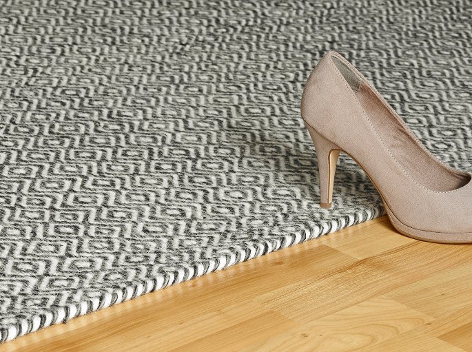 Texture d'un tissage naturel à motif géométrique noir et blanc sous un escarpin